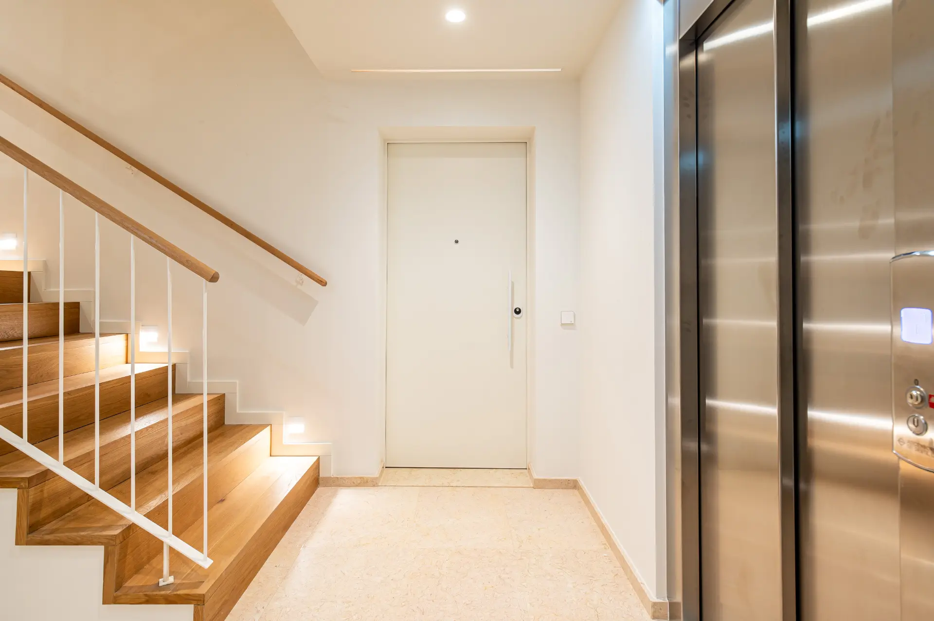 Hall comum com escadaria em madeira e elevador