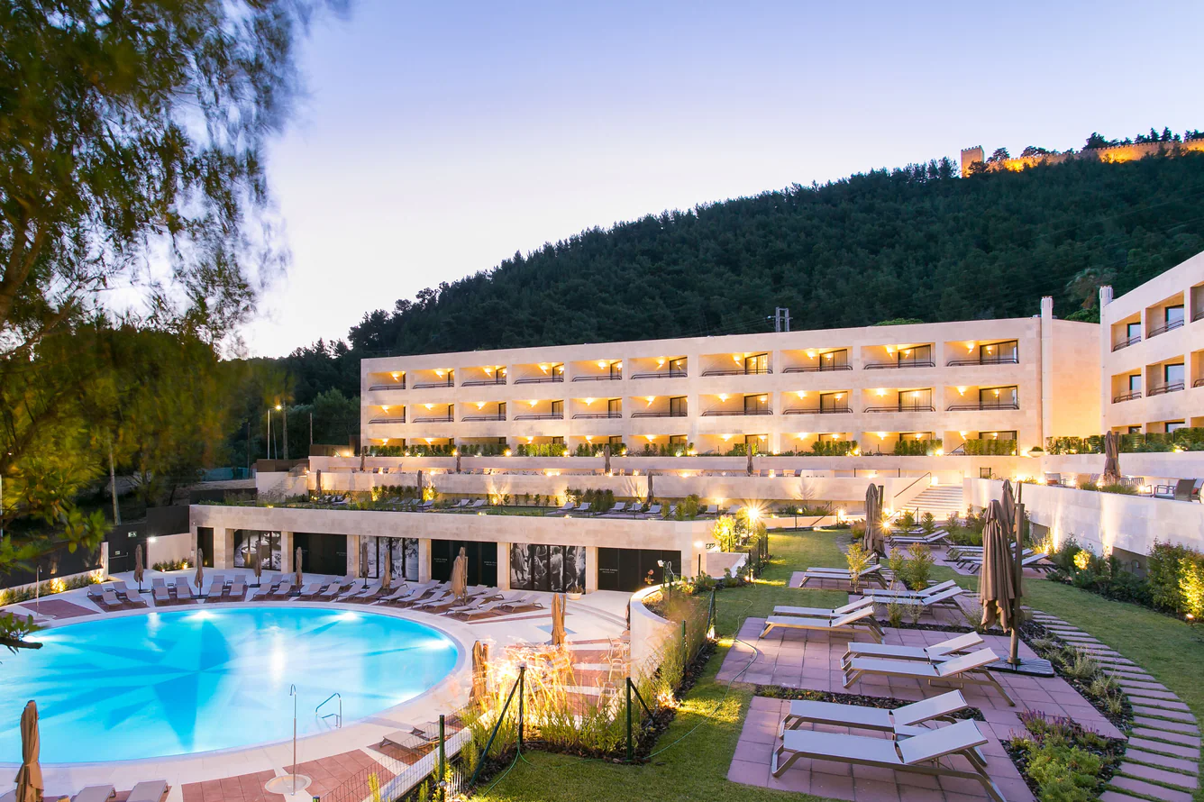 Piscina e fachada do hotel iluminadas ao anoitecer