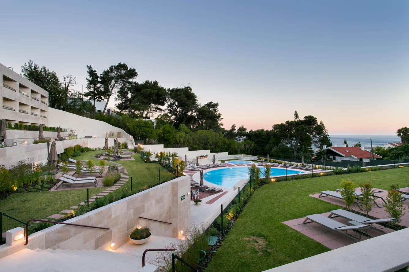 Jardim e piscina ao entardecer com vista para o Atlântico